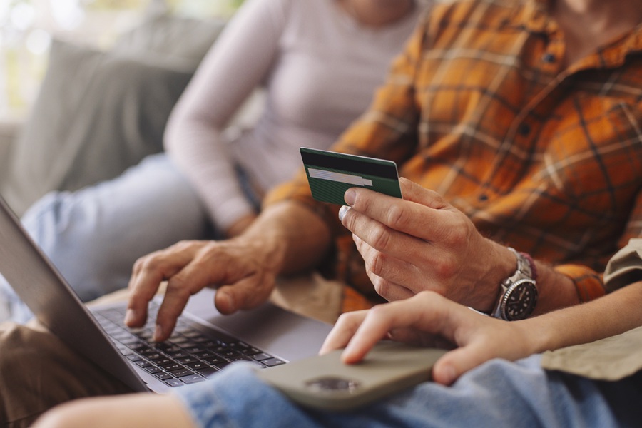 Billede af en, der sidder med sit dankort fremme foran computeren